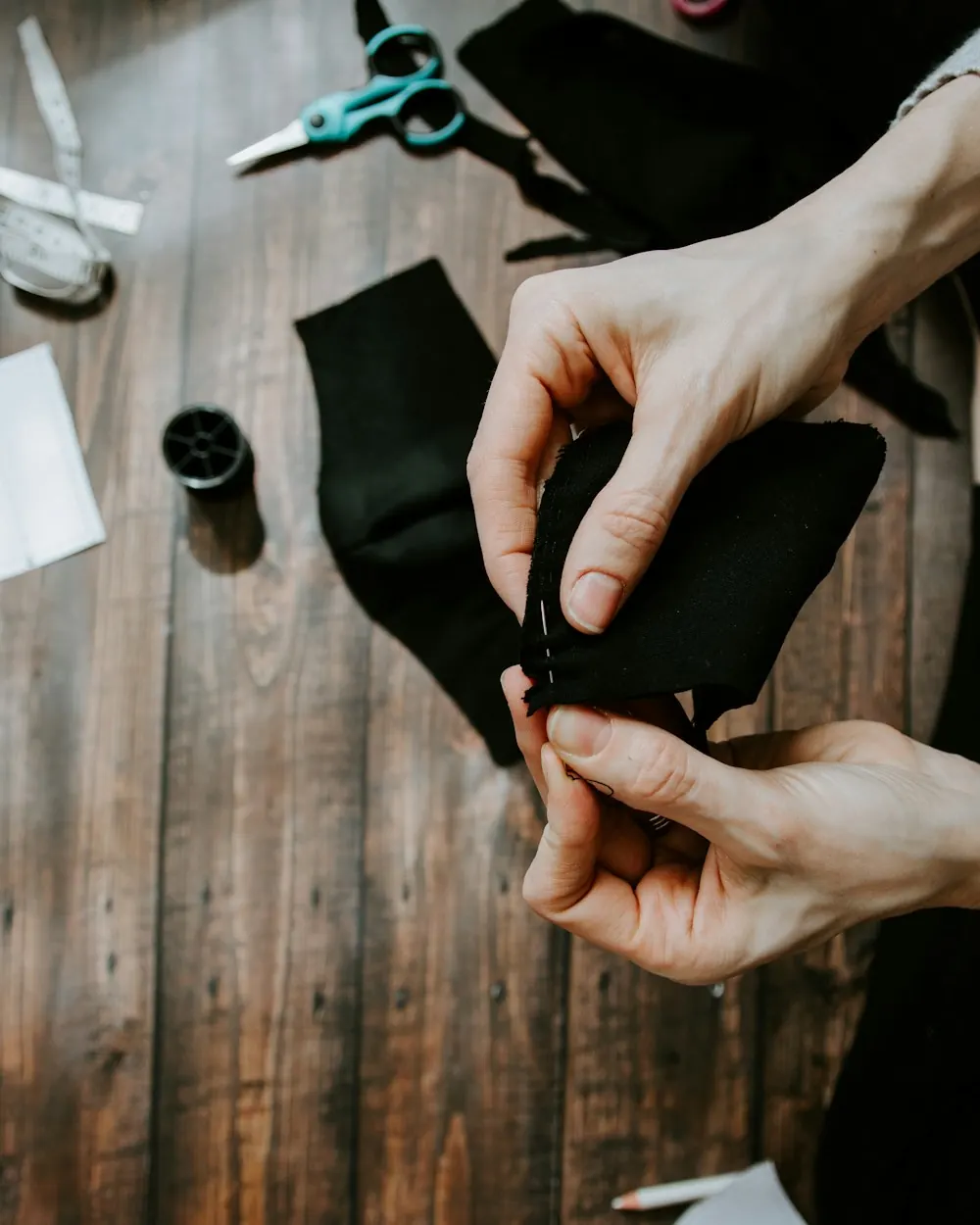 Manos cortando tela con tijeras sobre la mesa del taller